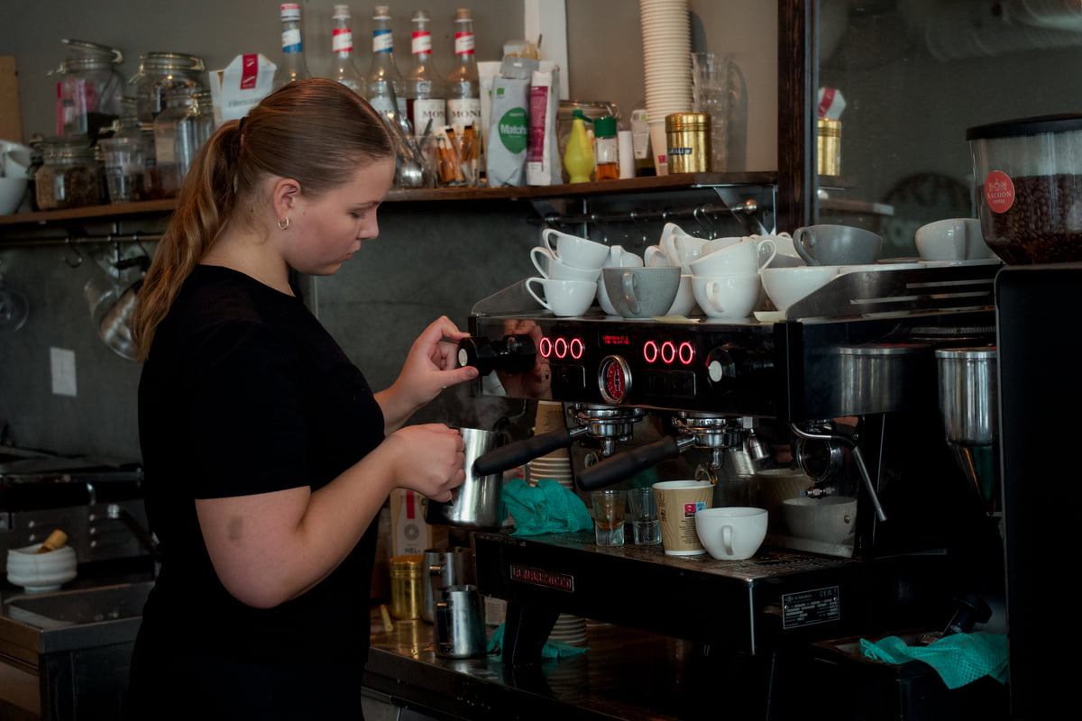 Jente som lager kaffe i kafe
