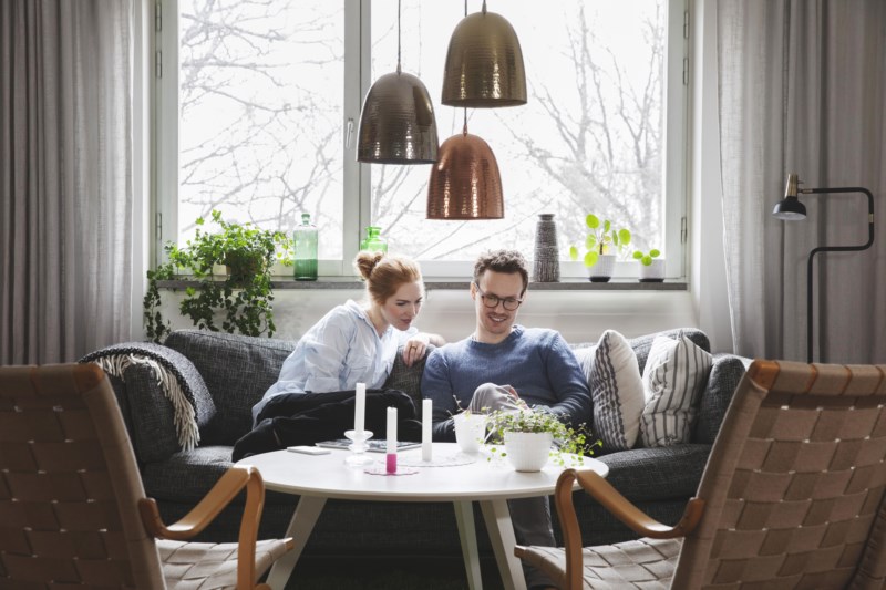 Ungt par som sitter i en sofa og ser på mobil