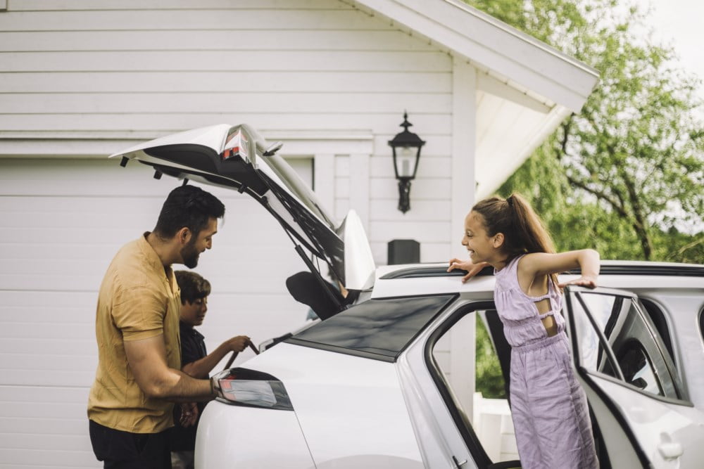 En familie i en avslappet og glad atmosfære mens de pakker bilen.