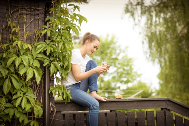 ung dame med mobil på verandaen